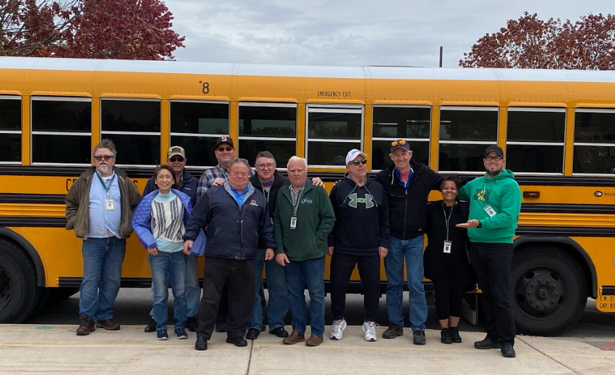 bus drivers standing in front of school bus