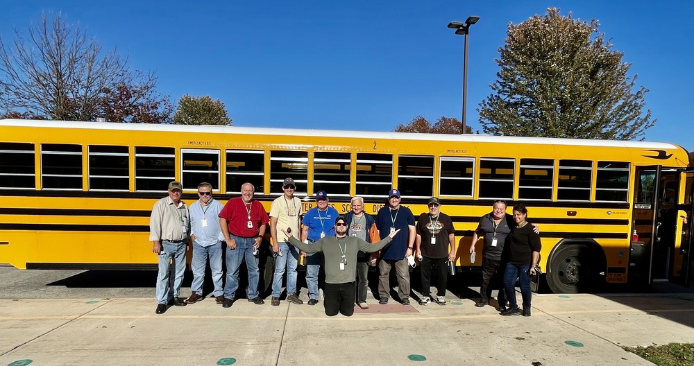 bus drivers standing in front of school bus