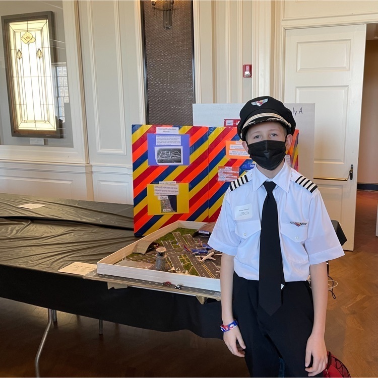 student wearing pilot uniform in front of project