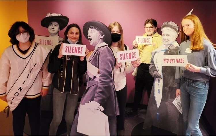 students standing with historical women display